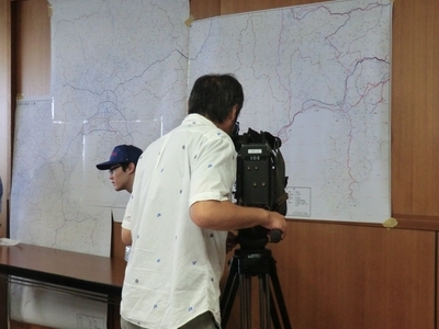 オペレーション室に提供された国土地理院作成の災害対策図を撮影する報道関係者