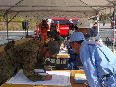UTMグリッド地図に救助要請や避難者の情報を書き込む陸上自衛隊員